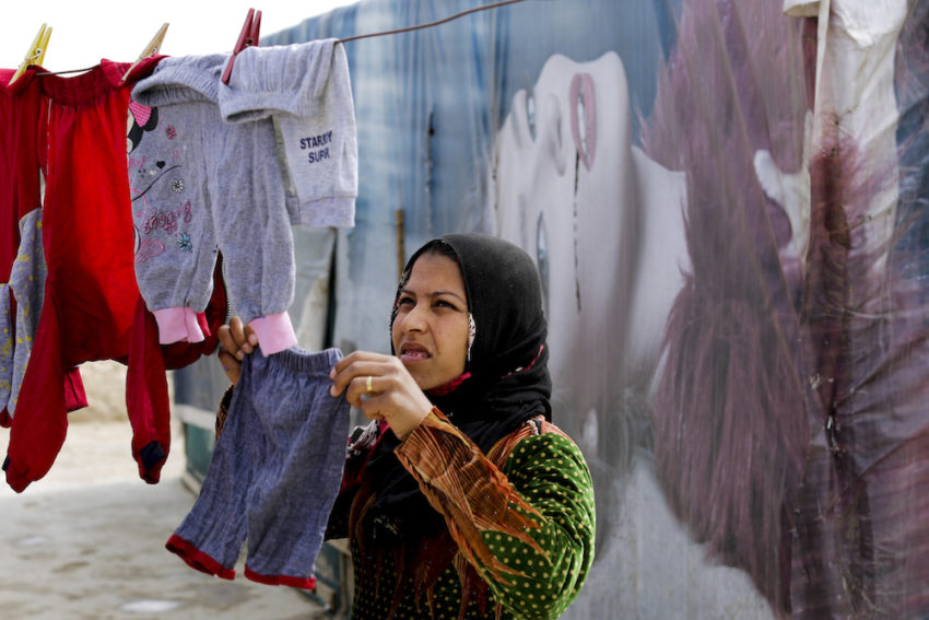 A Syrian refugee hanging her laundry at an informal refugee camp in Lebanon's Bekaa Valley.  (Hassan Ammar / AP)