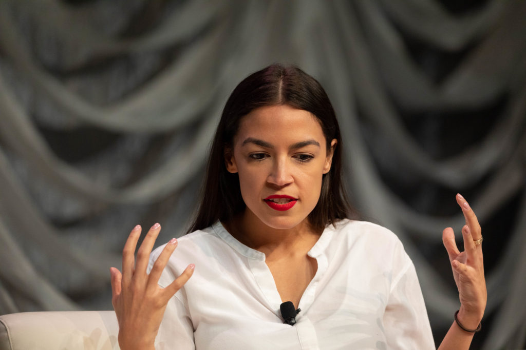 alexandria ocasio-cortez with her hands in the air