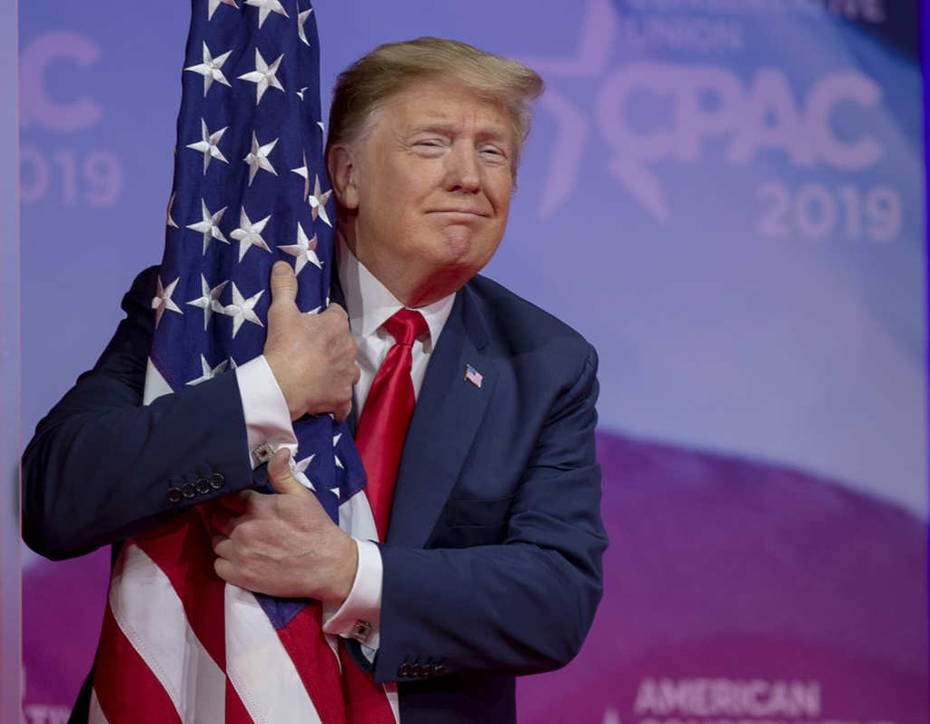 President Donald Trump hugs an American flag.