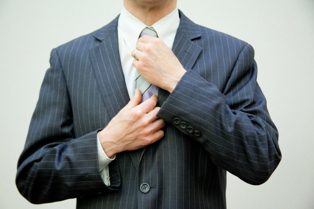 A man in a suit adjusts his collar.
