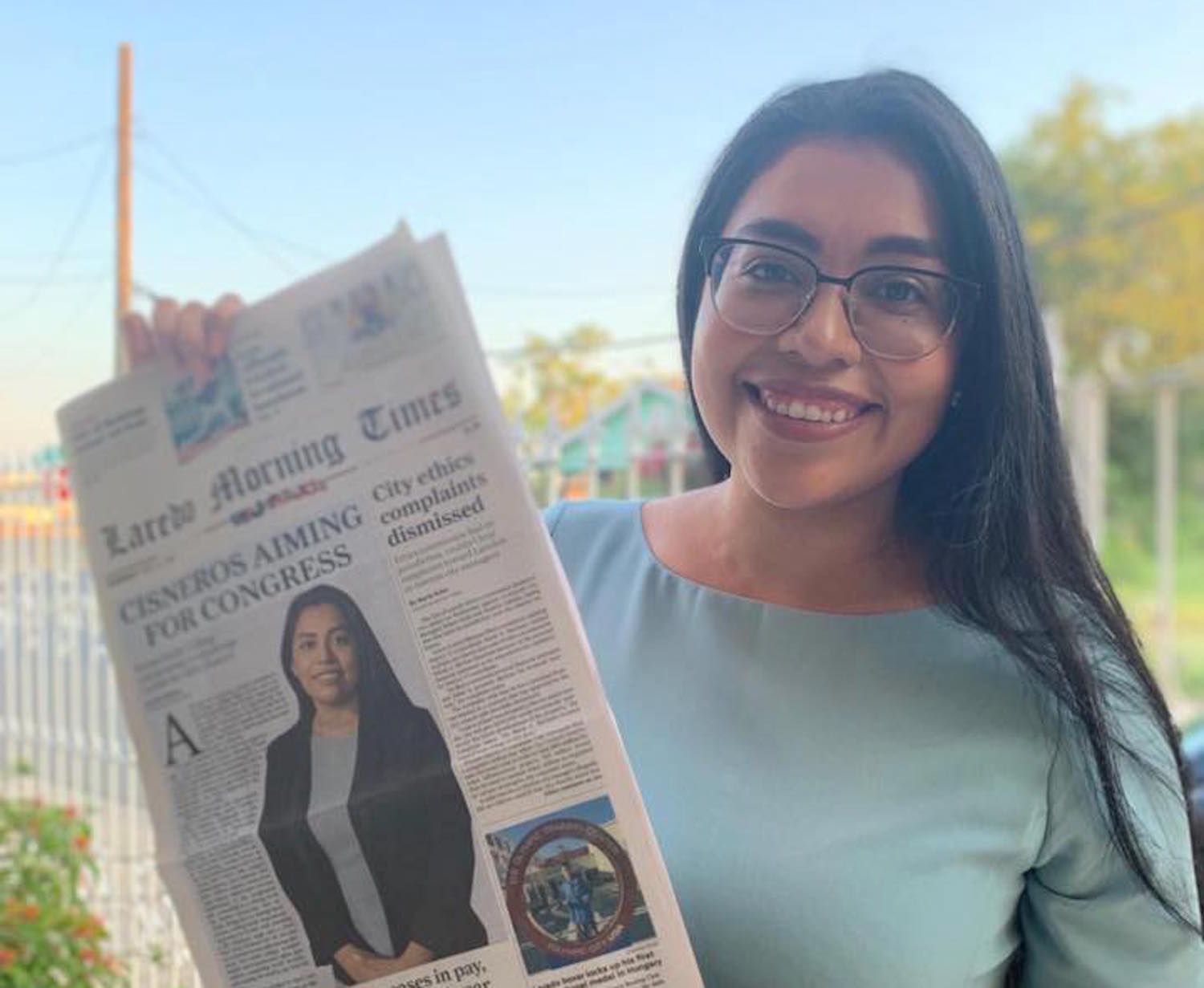 Jessica Cisneros holds up a newspaper with her face on it.
