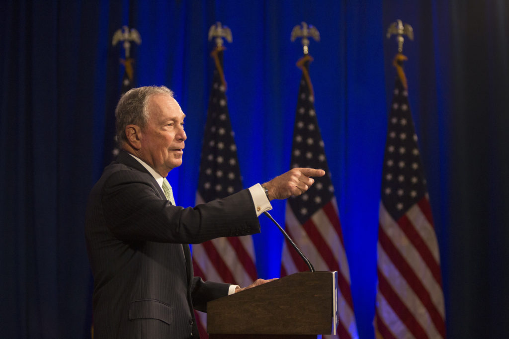 Michael Bloomberg in front of American flags