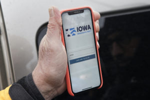 Hand holding a cell phone showing the Iowa Democratic Party's caucus reporting application
