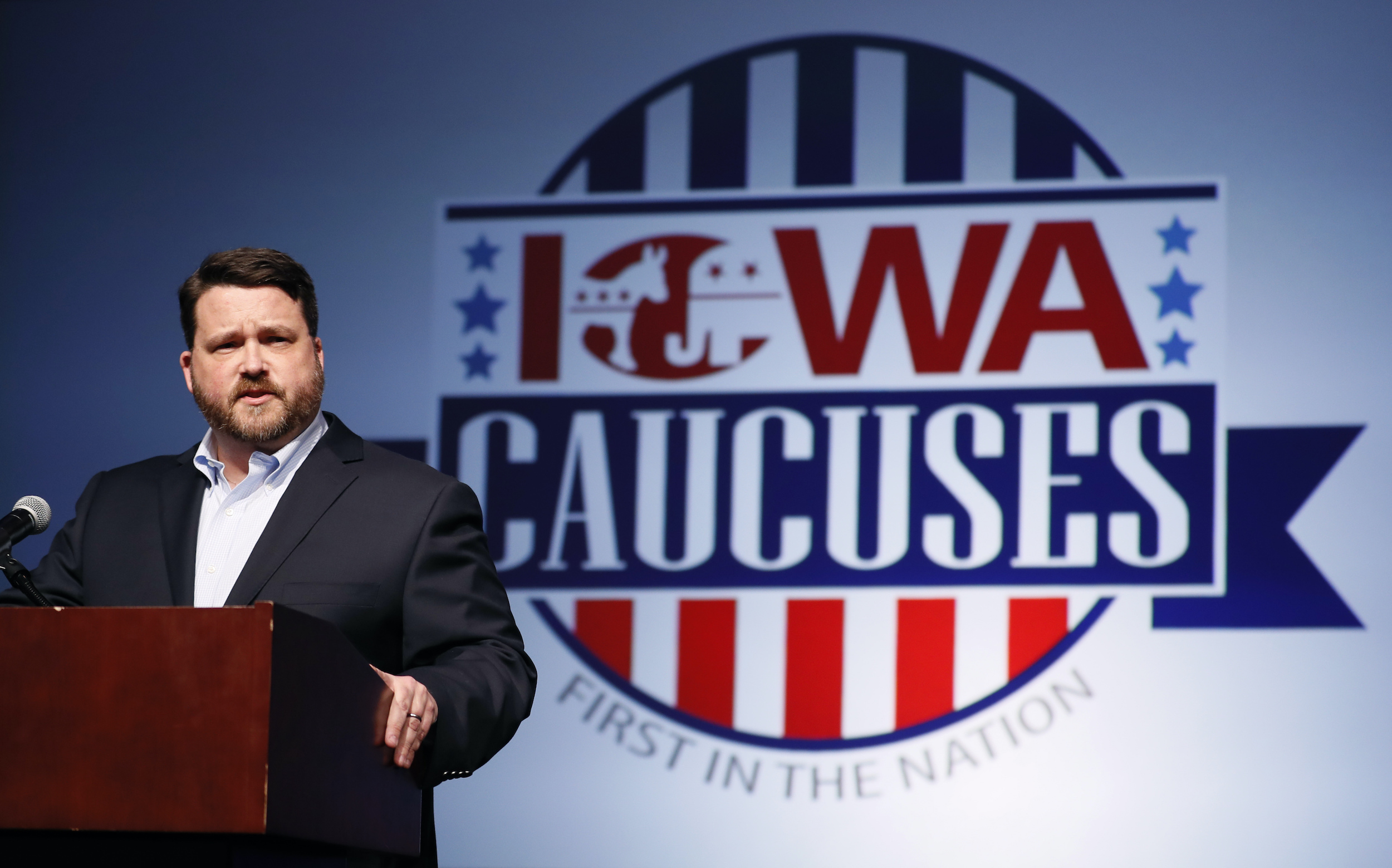 Iowa caucus 2020 sign with Iowa's DNC chair in front of the logo