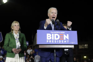 Joe Biden speaks on a podium and Jill Biden is behind him.