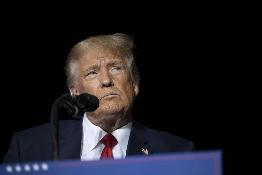 Donal Trump stands at a podium, looking angry