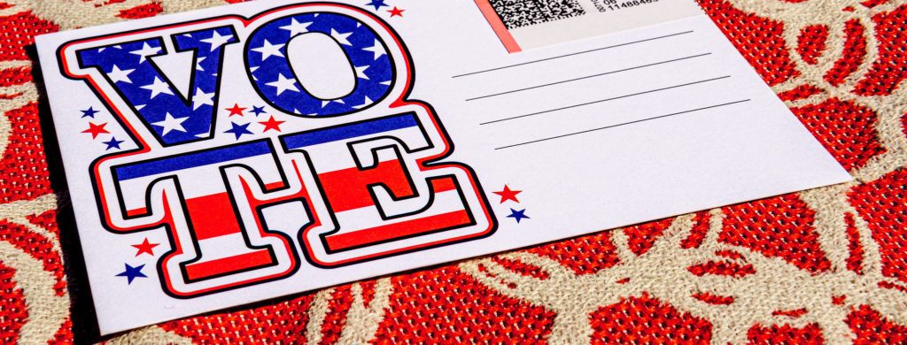 A postcard with "VOTE" on it. The stars and stripes of the American flag are within the bubble lettering of said "VOTE."