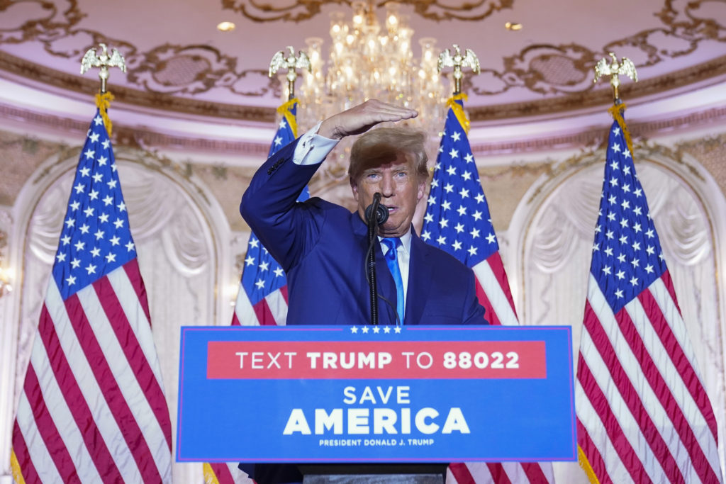 Donald Trump stands at a podium with American flags behind him