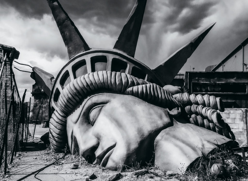 The head of the Statue of Liberty sits crushed on the ground.