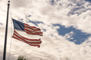 American flag torn down the middle waving in the wind.