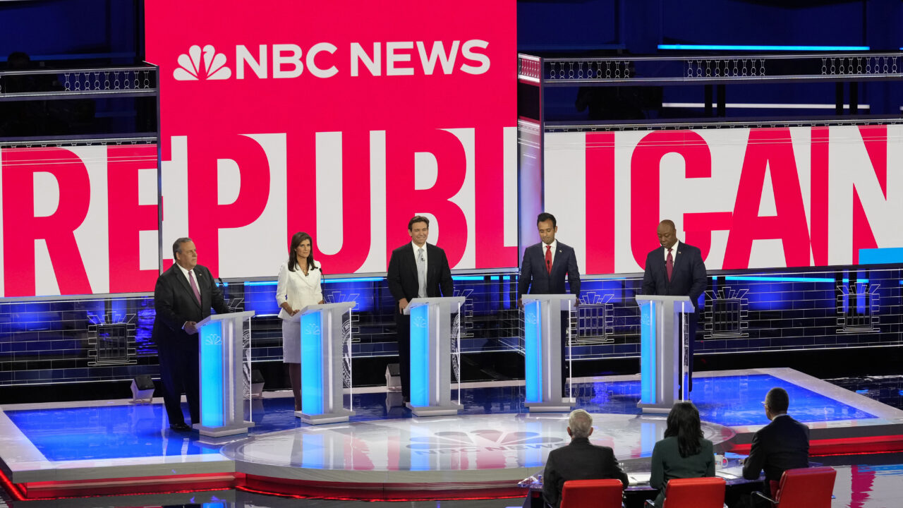 Republican presidential candidates from left to right Chris Christie, Nikki Haley, Ron DeSantis, Vivek Ramaswamy and Tim Scott stand at podiums on a debate stage, with the words "NBC News" displayed above them and "Republican Debate" behind them.