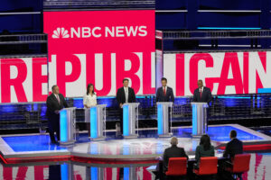 Republican presidential candidates from left to right Chris Christie, Nikki Haley, Ron DeSantis, Vivek Ramaswamy and Tim Scott stand at podiums on a debate stage, with the words "NBC News" displayed above them and "Republican Debate" behind them.